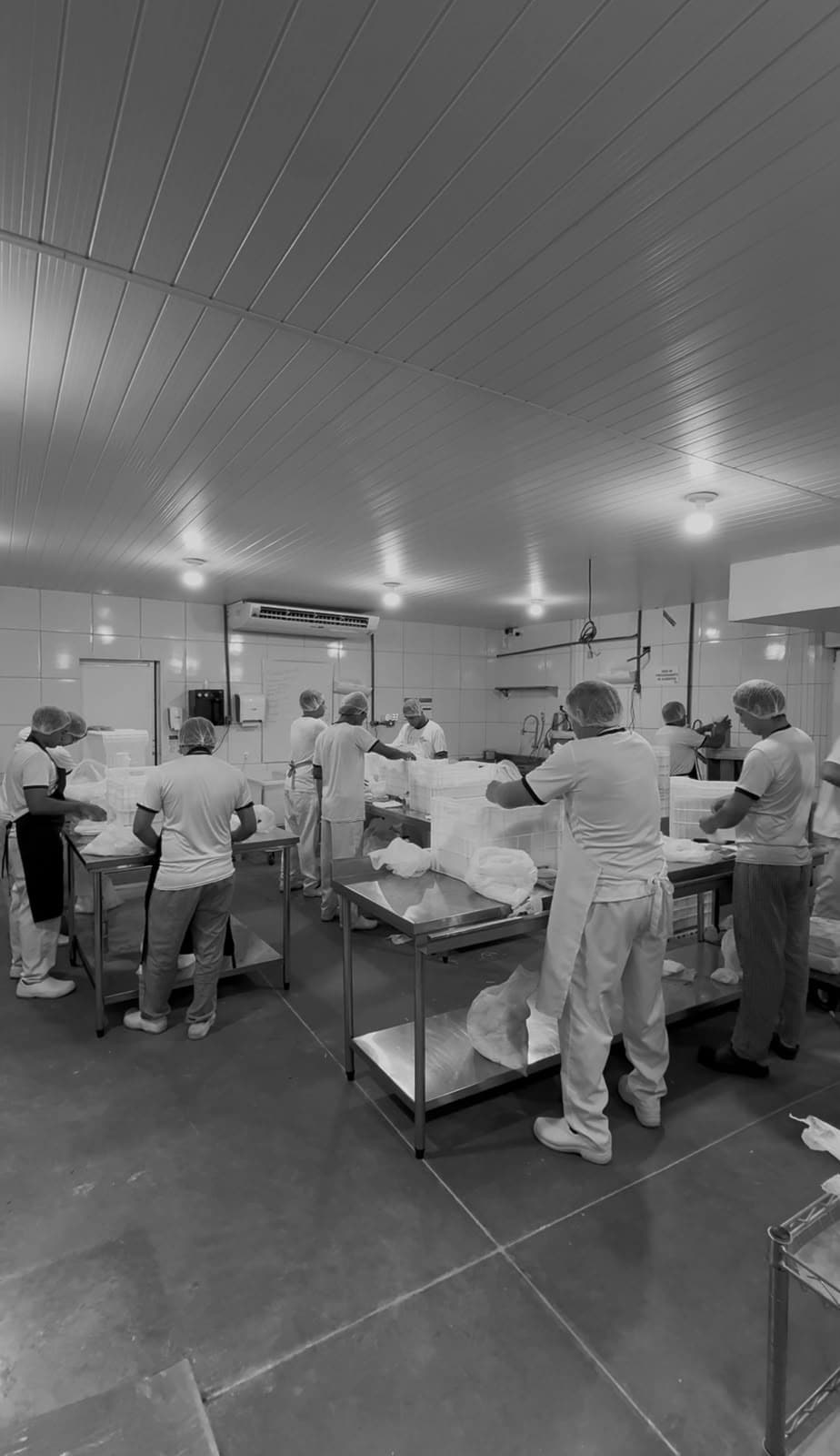 Brigada de cozinha de um cliente da Liberdata em produção, em bancadas de inox, com uniforme e touca.